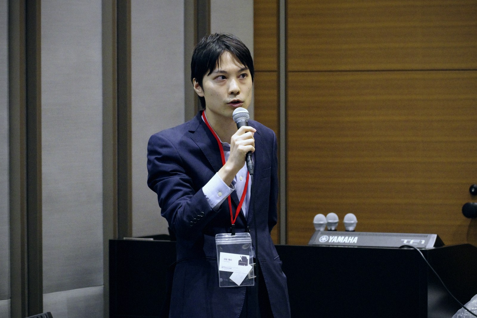 A speaker in a suit talking with a microphone in hand